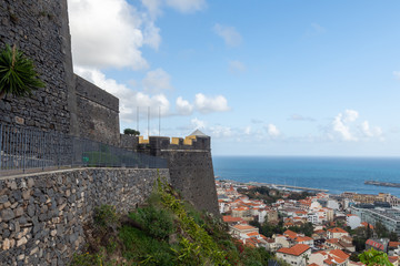 The São João Baptista fortres in foreground and part of the town and harbor with sea and blue sky with some clouds in background