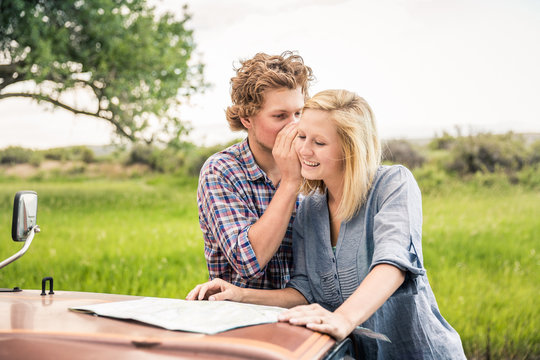 Young Couple Driving Through The Hills With An Old Jeep, Whispering In Each Others Ears. Bridger, Montana, USA