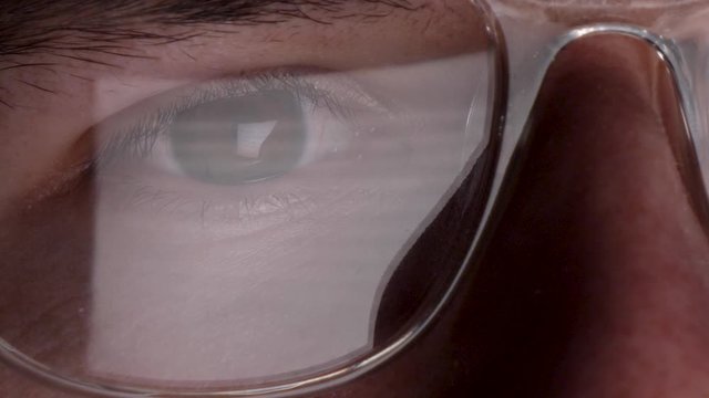 Close Up Of A Mans Eyes Looking At Computer Monitor Reflected In His Glasses. Locked Off