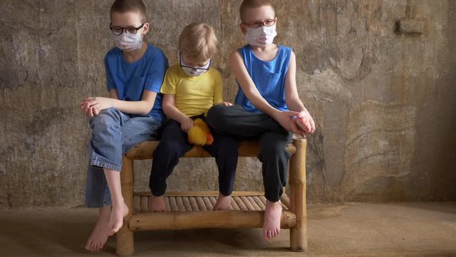 Three boys brothers in dirty medical masks are quarantined at home. Children cough heavily and quickly get dirty masks. concept of combating epidemic of coronavirus and proper prevention of infections