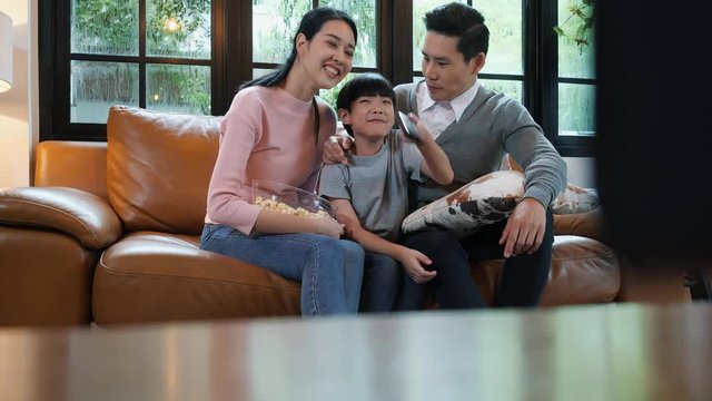 Happy anniversary asian family. Active father and mother with son looking movie entertainment in modern house living room. Little boy having fun enjoy funny activity together at home.