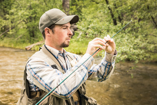 Portrait of fly fisherman feeding line through his rod next to stream. Red Lodge, Montana, USA