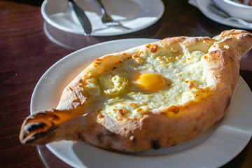 Khachapuri in Georgian restaurant - Georgian national cheese bread product, pie stuffed with cheese and eggs - Adjara Khachapuri is a famous dish from Georgia