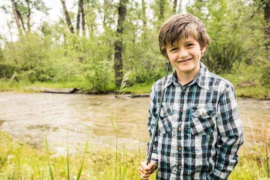 Portrait of young boy fly fishing next to stream. Red Lodge, Montana, USA