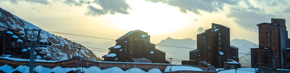 Snowy mountains and ski lifts. Downhill lies the village.