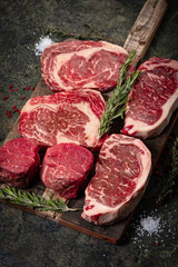 Set of Fresh raw marbled beef steaks on a wooden Board: tenderloin, Striploin, ribeye and rosemary