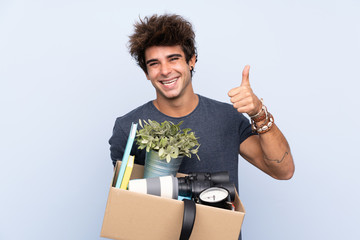 Man making a move while picking up a box full of things giving a thumbs up gesture