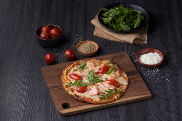 A very thin pizza topping with salmon and cheese tomato.