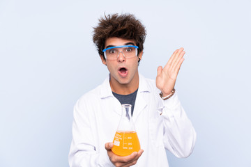 Young scientific man over isolated blue background with surprise facial expression