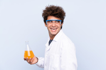 Young scientific man over isolated blue background laughing