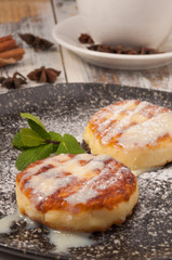 cheesecakes with condensed milk and a mint leaf on a dark plate