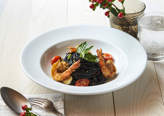 Black pasta fried with garlic prawn combine with mini tomato.