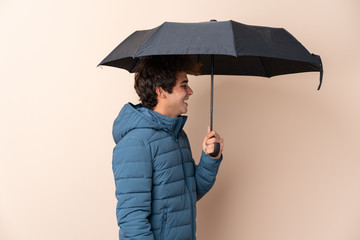Man holding an umbrella over isolated background with happy expression