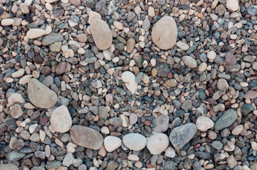 Textured background. Different size and shape grey stones on sea beach