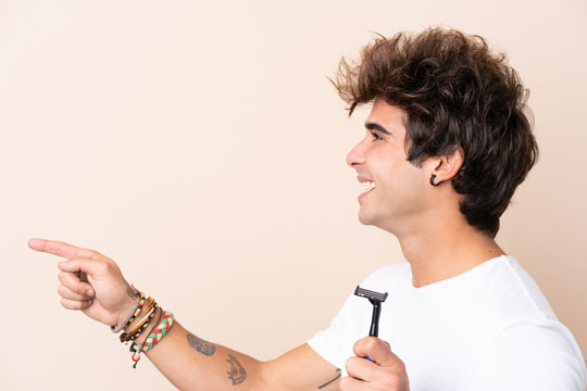Young handsome man shaving his beard pointing to the side to present a product