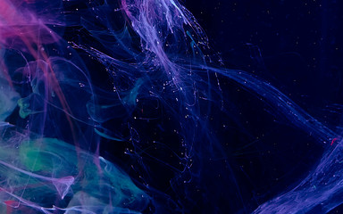 Colored watercolor ink in water on a black background.