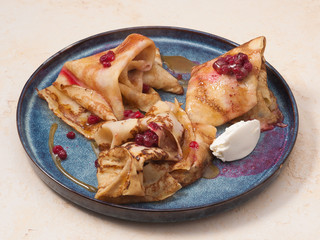 pancake with caramel cranberries on a blue plate on a light background