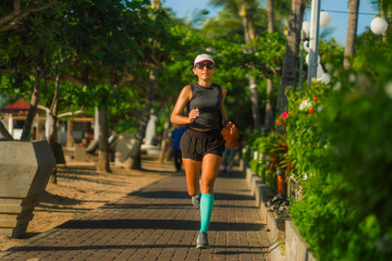 fitness lifestyle portrait of young attractive and athletic woman in compression running socks jogging happy on city park doing intervals workout in athlete training concept