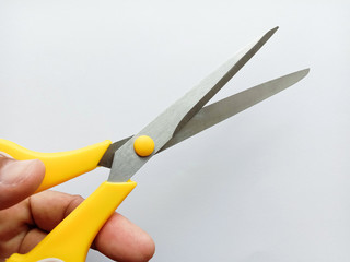 Scissors stainless steel yellow and white handle on hand isolated on white background closeup.