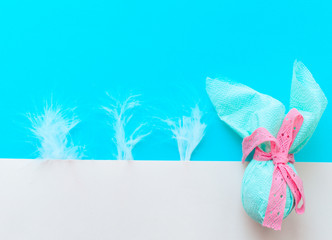 Egg gift in green paper packaging and with pink ribbon Easter Bunny wrap idea. multicolor colorful feathers. Minimal concept. Flat lay, Copy space, top view