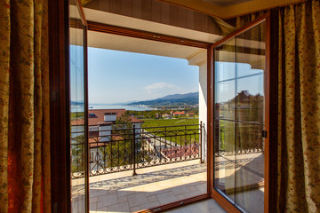 The open door on to the verandah of a luxury cabin with a view of the mountains and the sea.