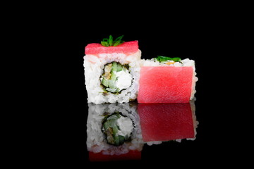 roll with tuna, avocado on a black background with insulation and reflection