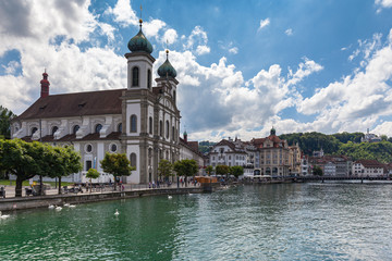 Fototapeta na wymiar Panoramal view of the Lucerne Jesuit Church (Jesuitenkirche) on Reuss river side in old town of Lucerne with reflection in water, on a sunny summer day with blue sky cloud, Switzerland
