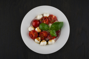 delicious salad with cherry tomatoes mozzarella and basil in a bowl on a black wooden table