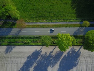 Mobilität: Auto auf einer Landstraße, daneben ein Radweg, Vogelperspektive