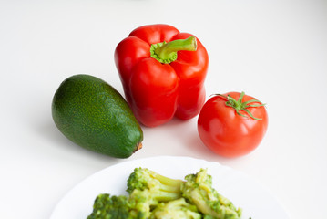 Vegetables red bell pepper, tomato and avocado, broccoli in a plate