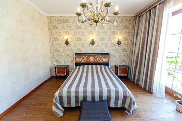 Elegant expensive bedroom with a large white bed with a striped bedspread. A high headboard with a...