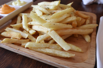 Tasty french fries on cutting board, on wooden table background.