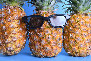 Pineapple in sunglasses close-up on blue background