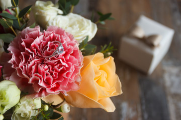 Silver ring and a bouquet of flowers, blurred background