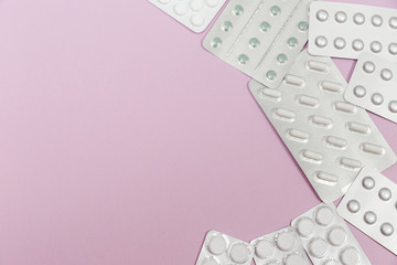 Pills in blister packs on a pink background
