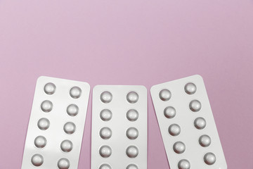 Pills in blister packs on a pink background