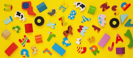 Banner with many small colorful wooden toys on yellow background,