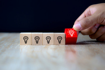 Close-up image of hand-picked cube shaped wooden toy blocks with light bulb symbol stacked ideas...