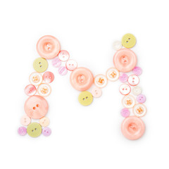 Letter M from pink and green buttons isolated on white background. Sewing kit. Colorful buttons, stylish alphabet for handmaking hobby. Handmade sew abc. Text from buttons