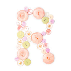 Letter R from pink and green buttons isolated on white background. Sewing kit. Colorful buttons, stylish alphabet for handmaking hobby. Handmade sew abc. Text from buttons