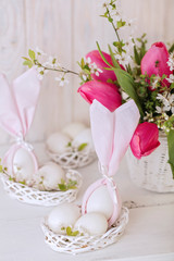 Happy easter. Decor and table setting of the Easter table is a vase with pink tulips and dishes of pink and green color.