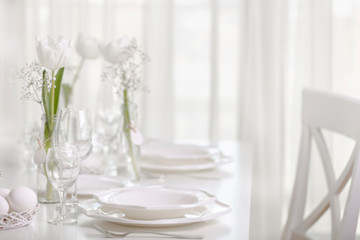 Happy Easter! Decor and table setting of the Easter table with white tulips and dishes of white color.