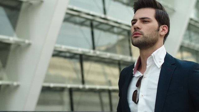 Portrait man looking away at street. Businessman checking time on watch outdoors