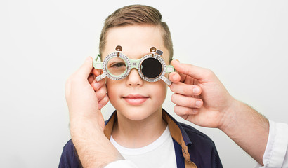 Optometrist putting on the boy special glasses to restore visual acuity. Amblyopia treatment in an...