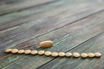 Beige pill on a wooden background with copy space.