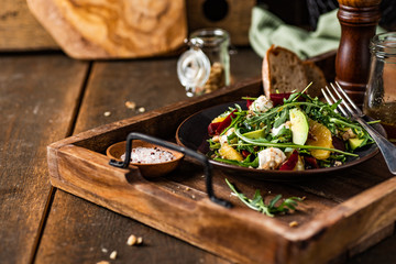 Fresh arugula salad with mozzarella, avocado, beetroot, walnuts and oranges. Espresso and orange juice dressing. Served on wooden tray. 
