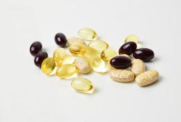 Scattered pills on a white background. Astaxanthin, fish oil and vitamins. Close-up.