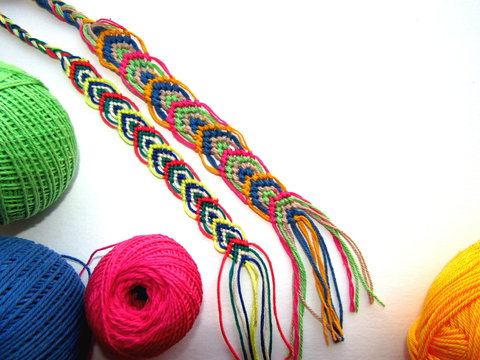 Braided friendship bracelets made of thread with a ball on a white background