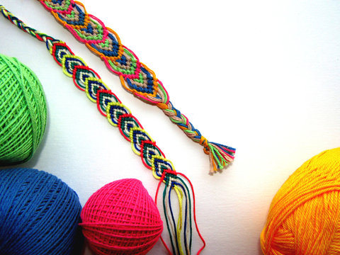 Braided friendship bracelets made of thread with a ball on a white background