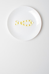 Omega-3 polyunsaturated fatty acids on a plate. Fish oil softgels on a white plate in a shape of a fish. Meal replacement. Casual  nutrition prescription. Copy space below.